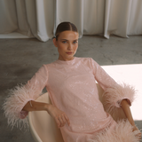 A round neckline pink sequin mini dress with ostrich feathers around the 3/4 sleeves and the skirt hemline | Gina Kim