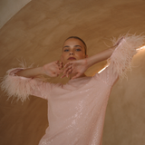 A round neckline pink sequin mini dress with ostrich feathers around the 3/4 sleeves and the skirt hemline | Gina Kim