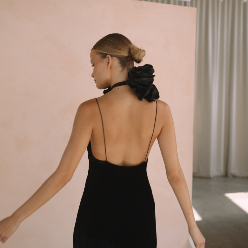 Woman wearing a black velvet dress with floral neck choker from the back| Gina Kim