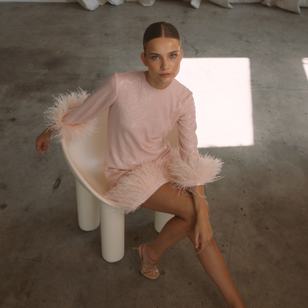 A round neckline pink sequin mini dress with ostrich feathers around the 3/4 sleeves and the skirt hemline | Gina Kim